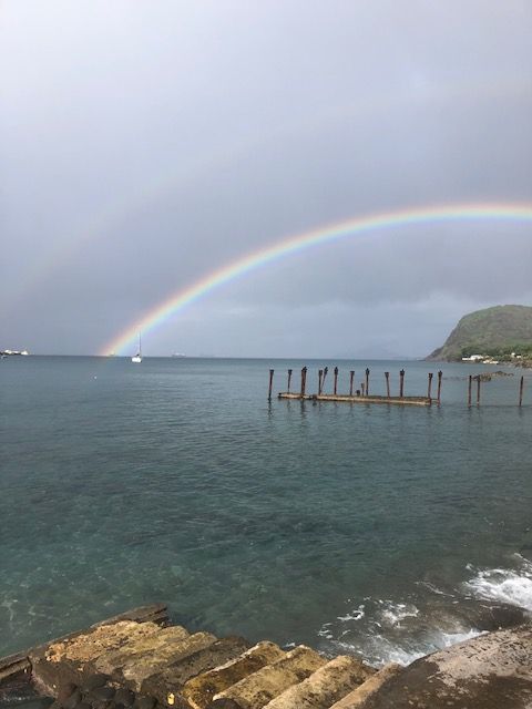 Een regenboog boven een watermassa met een dok op de voorgrond