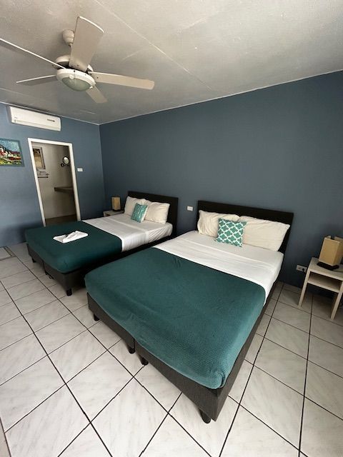 Een hotelkamer met twee bedden en een plafondventilator