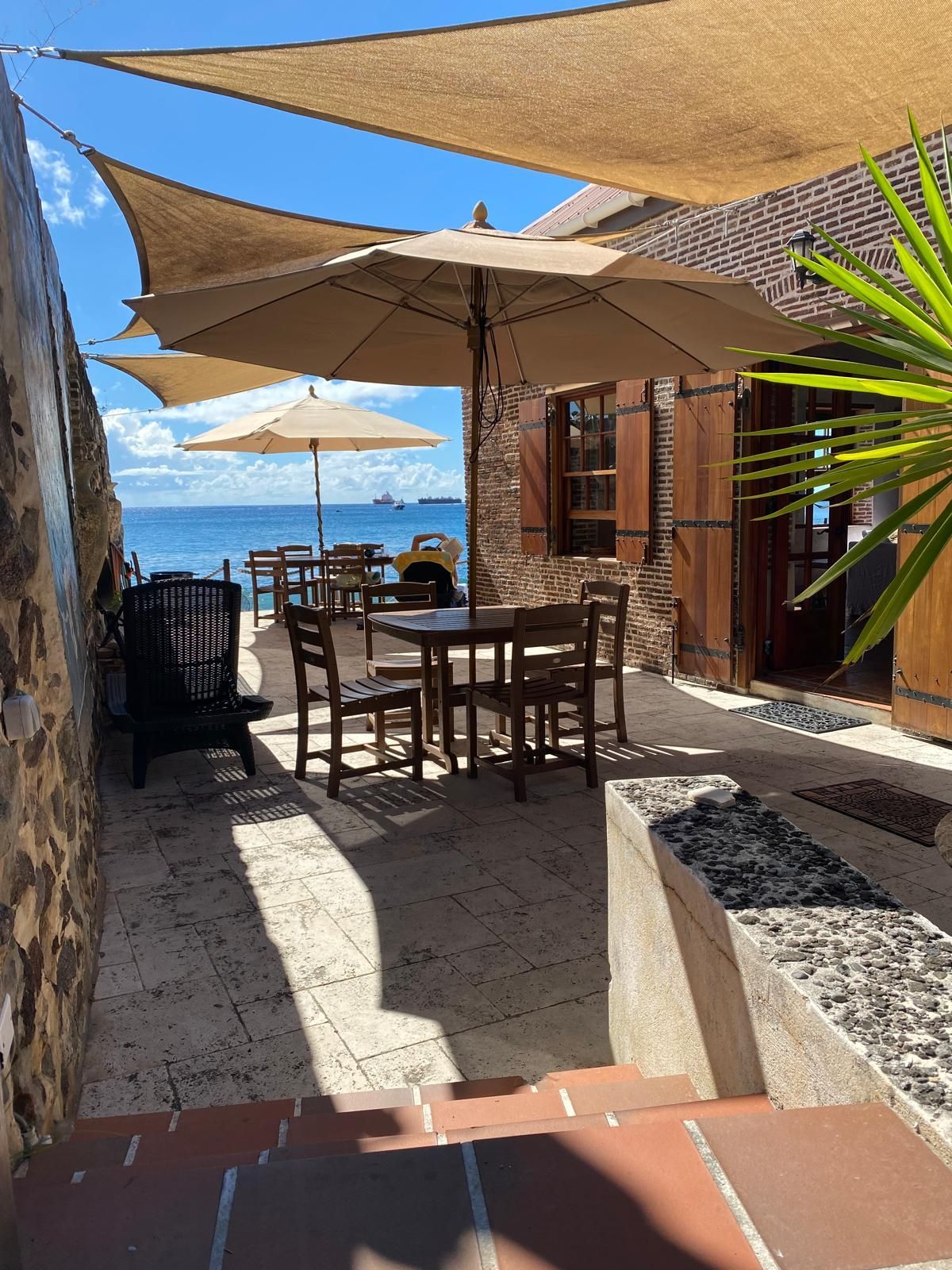 Een terras met tafels, stoelen en parasols met uitzicht op de oceaan.