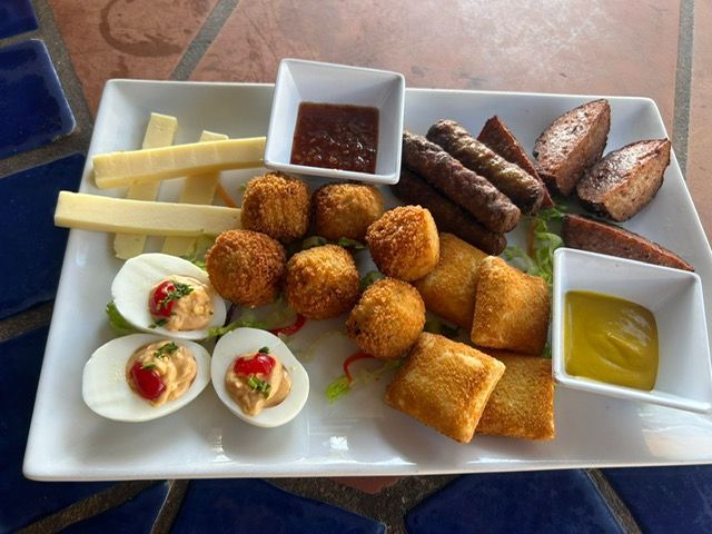 Een wit bord belegd met diverse soorten eten en sauzen.