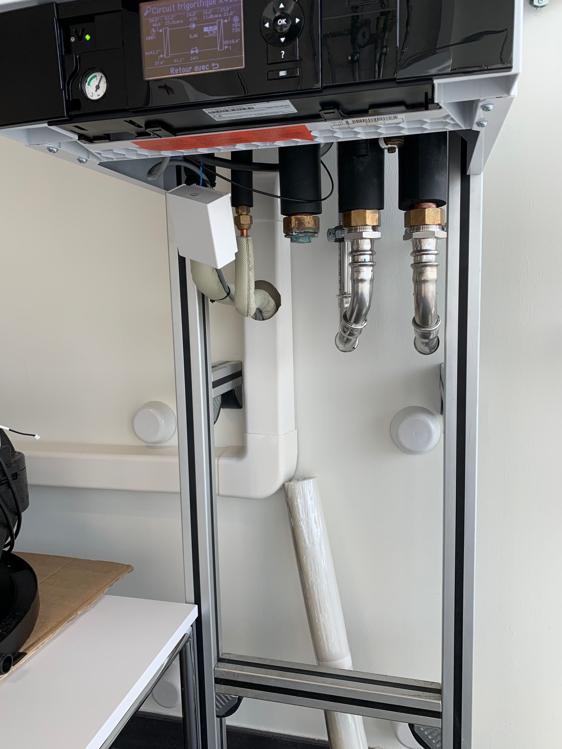 Matériel de laboratoire avec buses suspendues, monté sur un cadre métallique et un mur blanc.