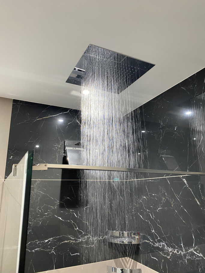 Pommeau de douche pulvérisant de l'eau, murs en marbre noir.