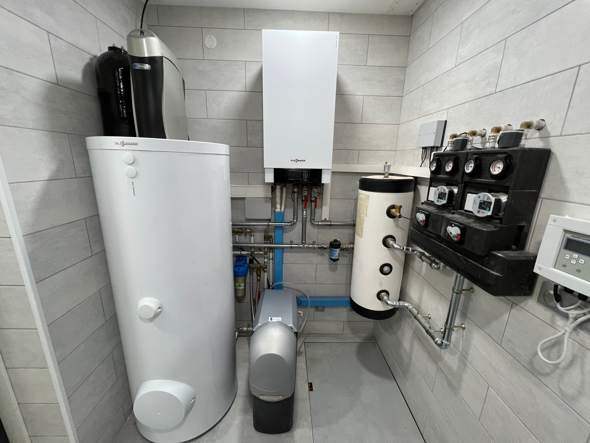 Une buanderie avec chauffe-eau, système de chauffage, tuyauterie et panneau de contrôle.