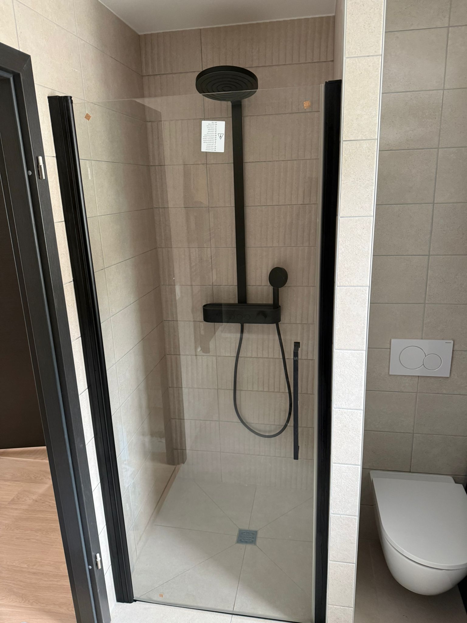 Salle de bains moderne avec carrelage bleu sarcelle et blanc, douche en verre, vanité en bois et lavabo blanc.