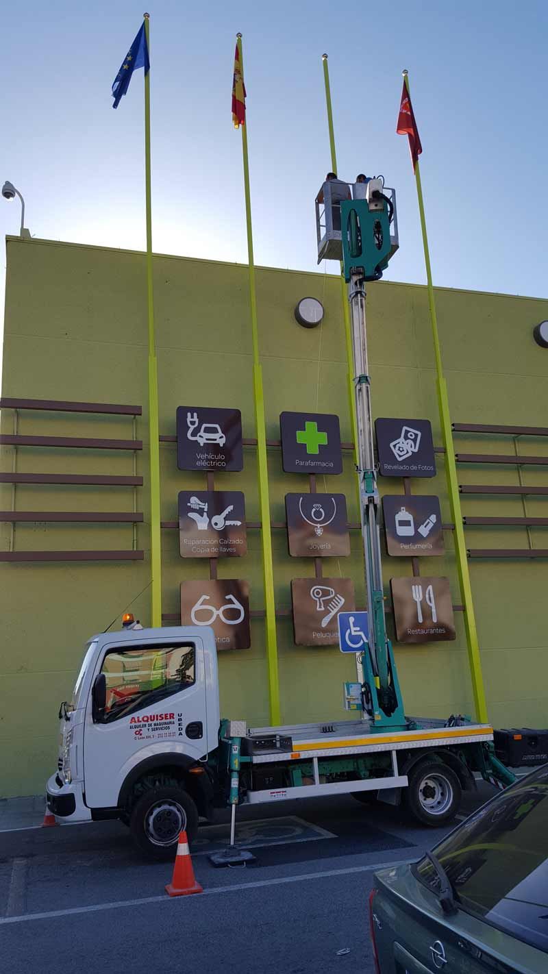 Un camión con una grúa encima está estacionado frente a un edificio.
