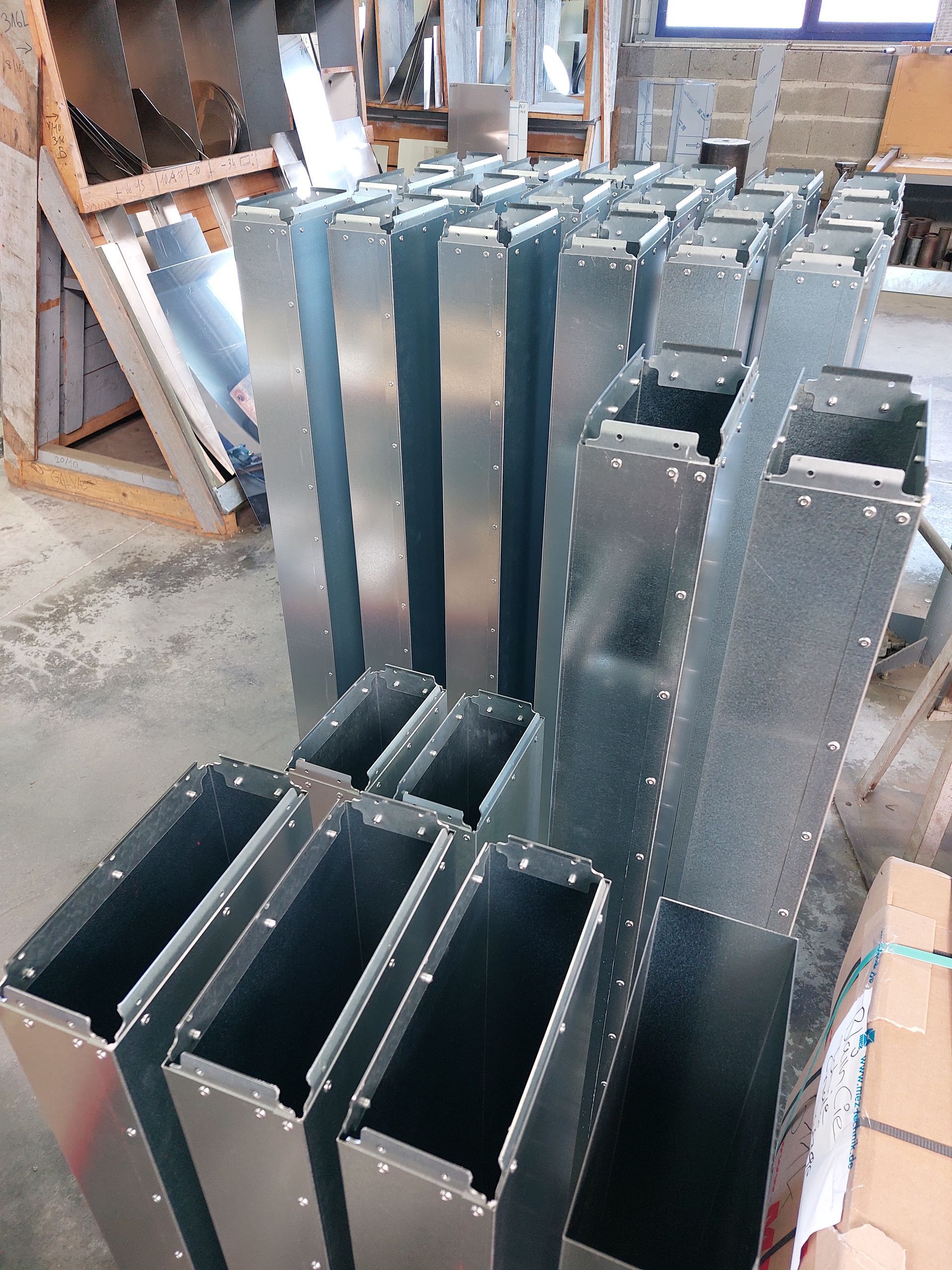 Les conduits métalliques de climatisation traversent un plafond industriel et sont fixés à des poutres en acier.