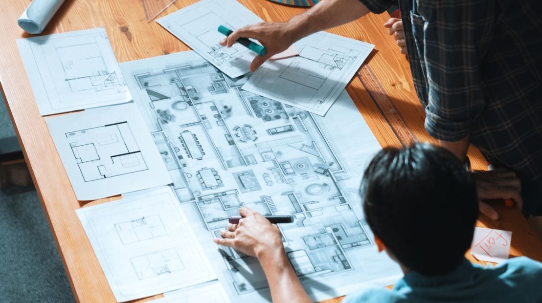 Dos personas mirando planos arquitectónicos sobre una mesa de madera.