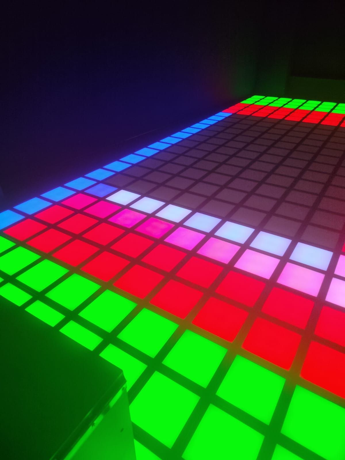 Cuadrícula de neón brillante con cuadrados LED de colores rojo, verde, azul y rosa sobre un fondo oscuro