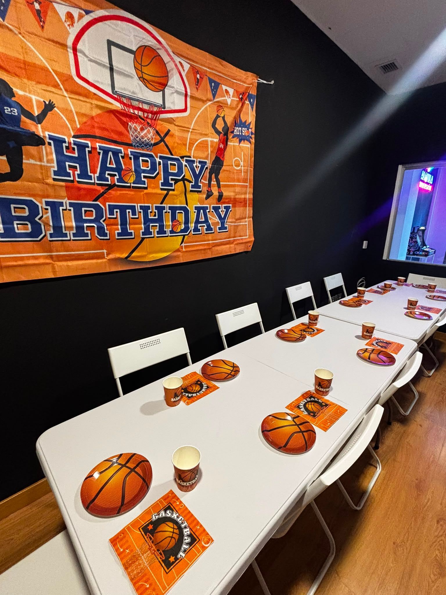 Mesa de cumpleaños temática de baloncesto, con adornos naranjas y una gran pancarta de «Feliz cumpleaños»