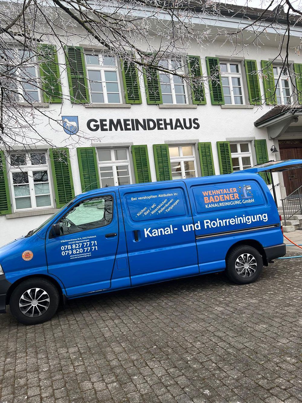 Vor einem Gebäude parkt ein blauer Lieferwagen.