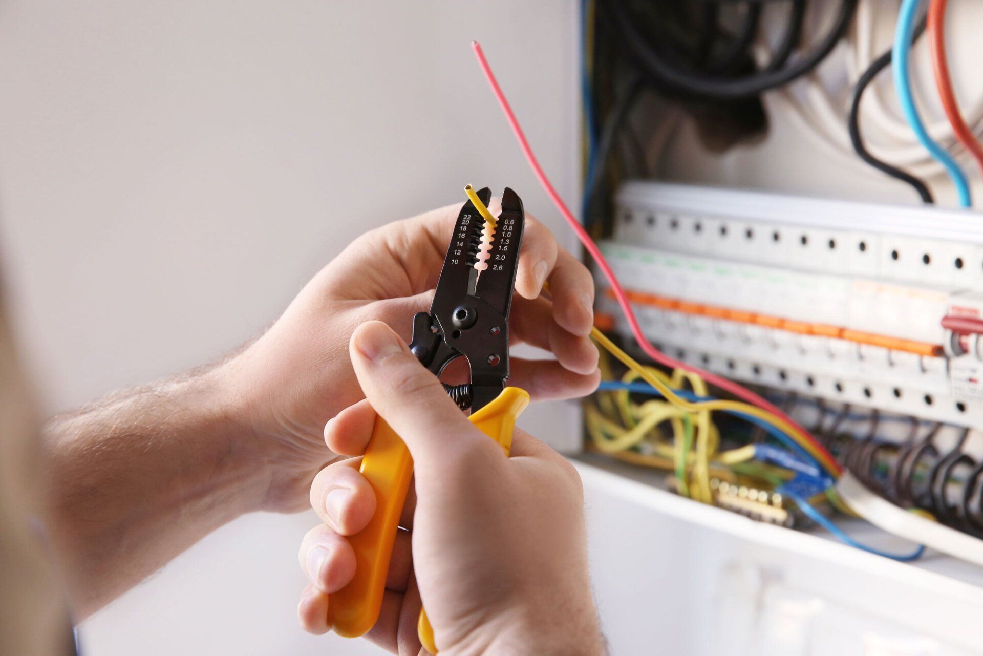 Électricien en train de dénuder un fil avec une pince