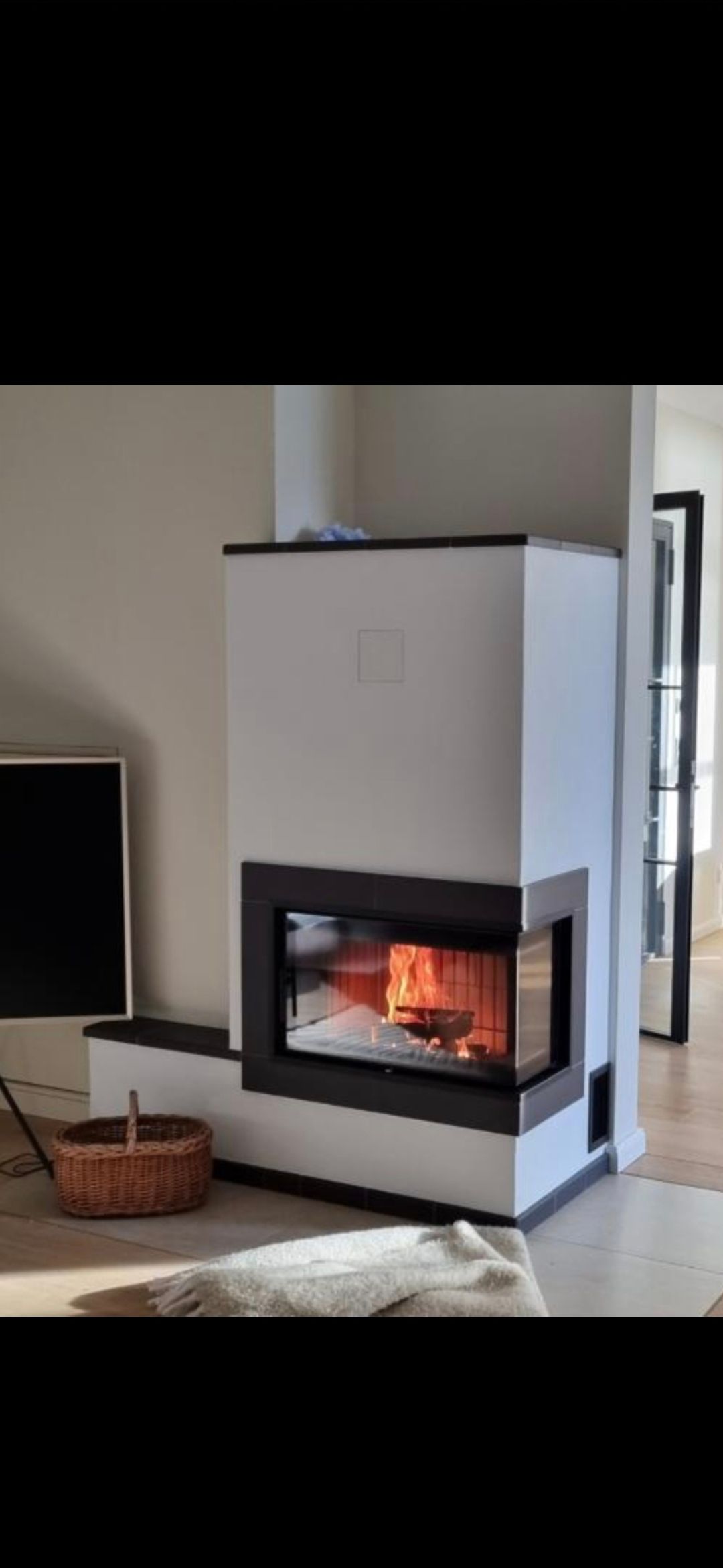 Weißer Kamin mit einem schwarz umrandeten Feuer im Inneren.