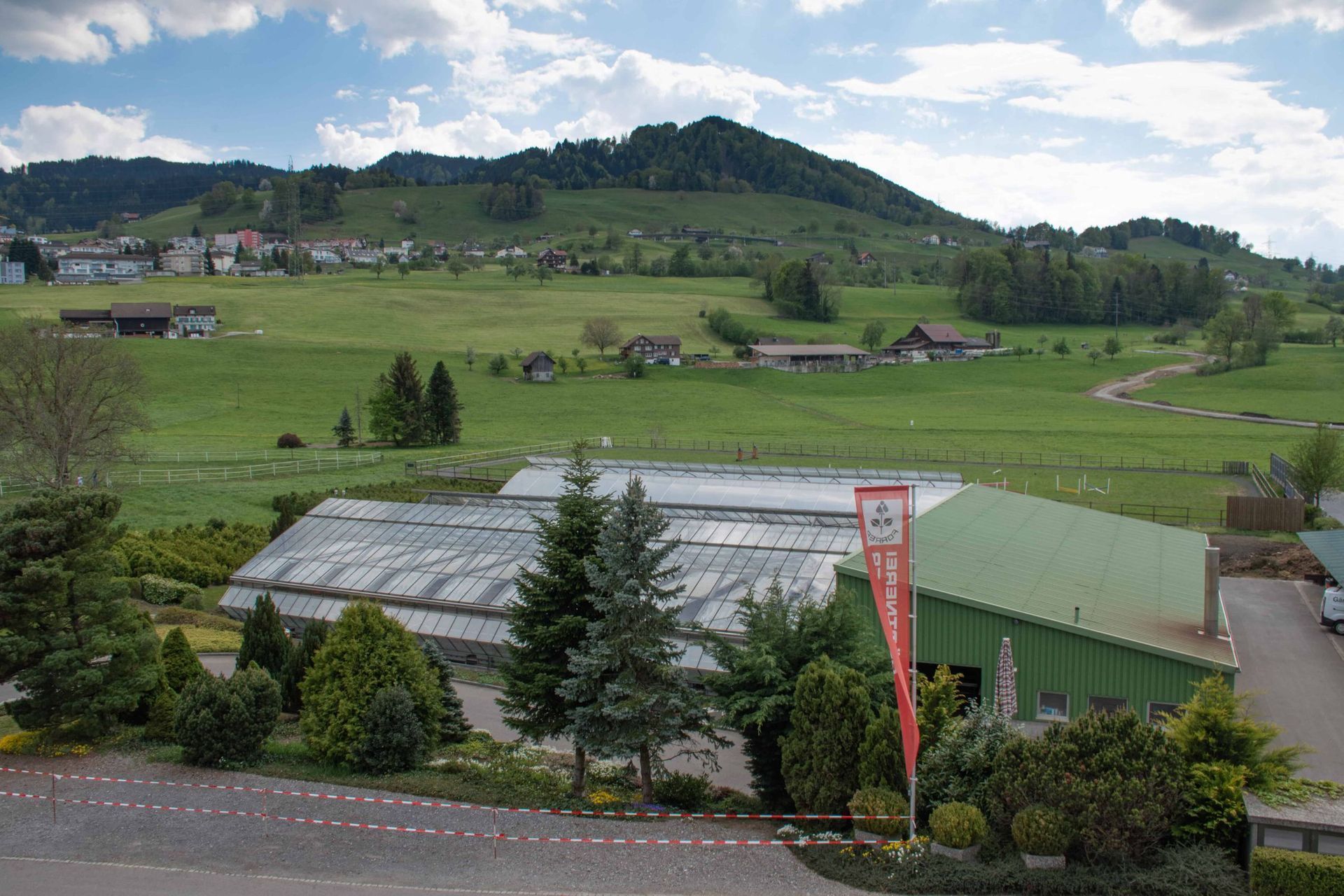 Ein Gewächshaus inmitten eines üppigen grünen Feldes. Foto von der Gärtnerei Forrer