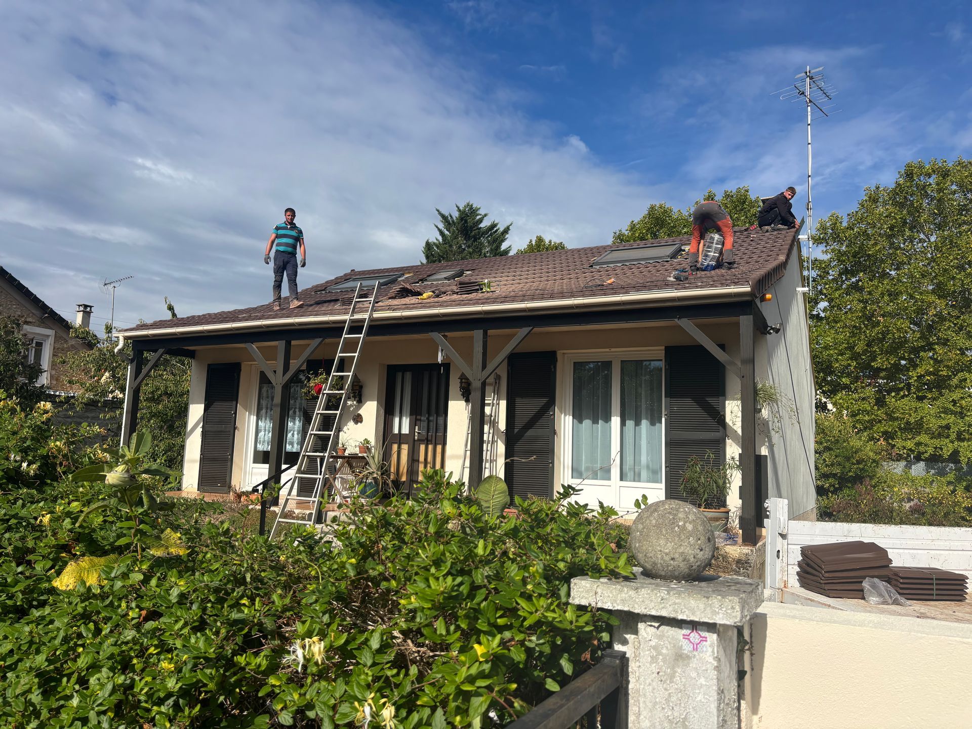 Toiture d'une maison en cours de réparation, ouvriers sur le toit.