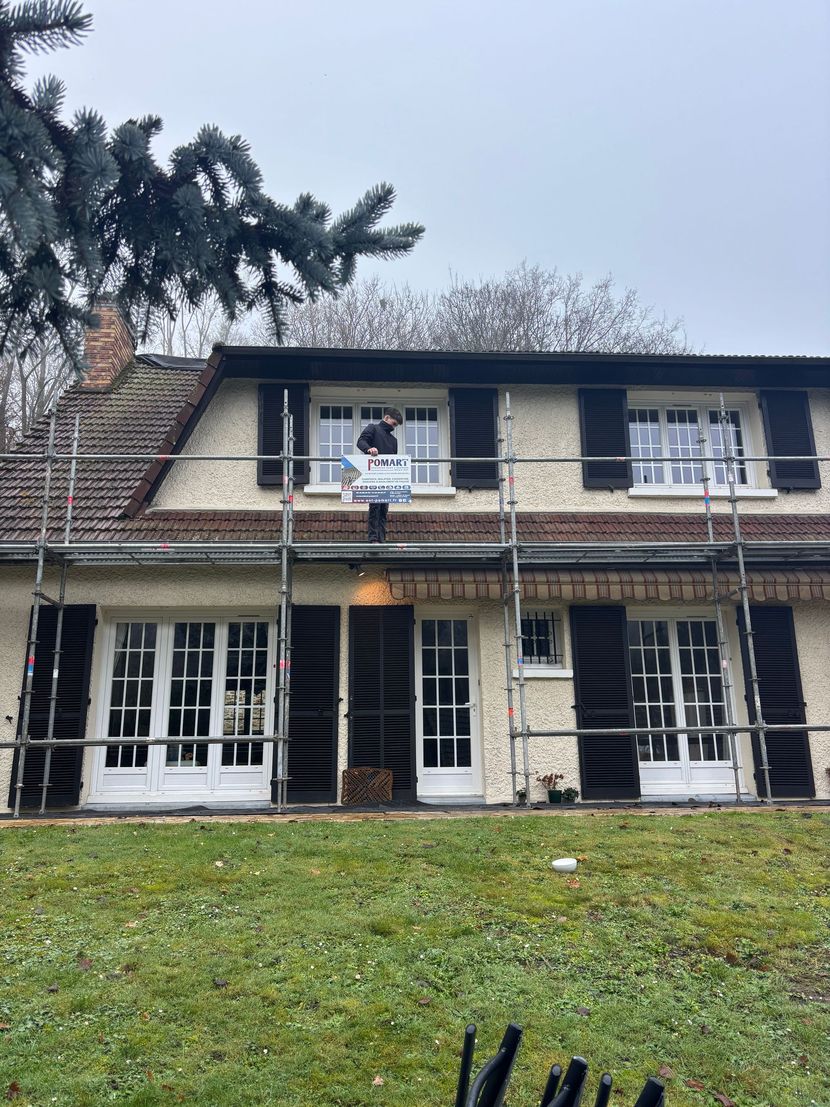 Maison à deux étages avec une personne sur un échafaudage.