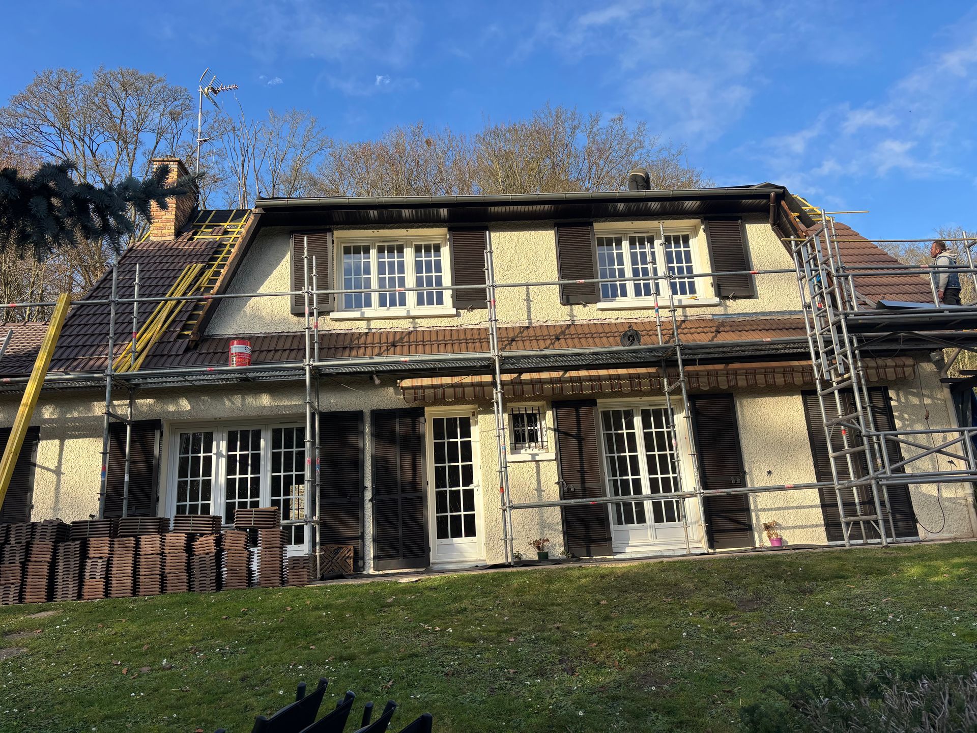Une maison de campagne avec des échafaudage pour des travaux de toiture.