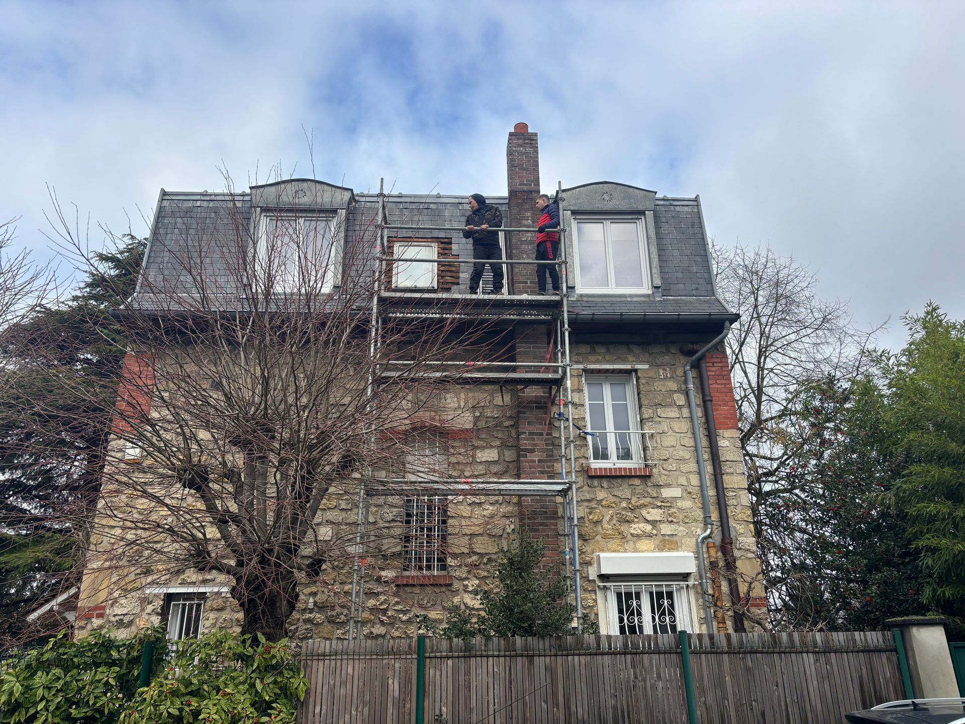 Des membres de l'entreprise Artisan Pomart sur un échafaudage pour les travaux d'une maison.