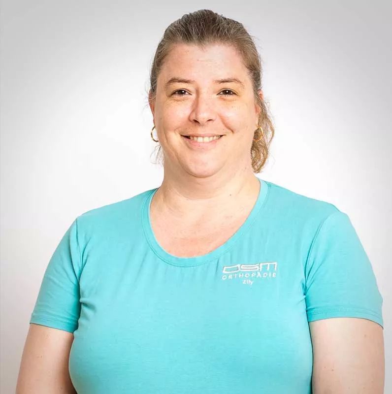 Eine Frau trägt ein blaues T-Shirt und lächelt in die Kamera.