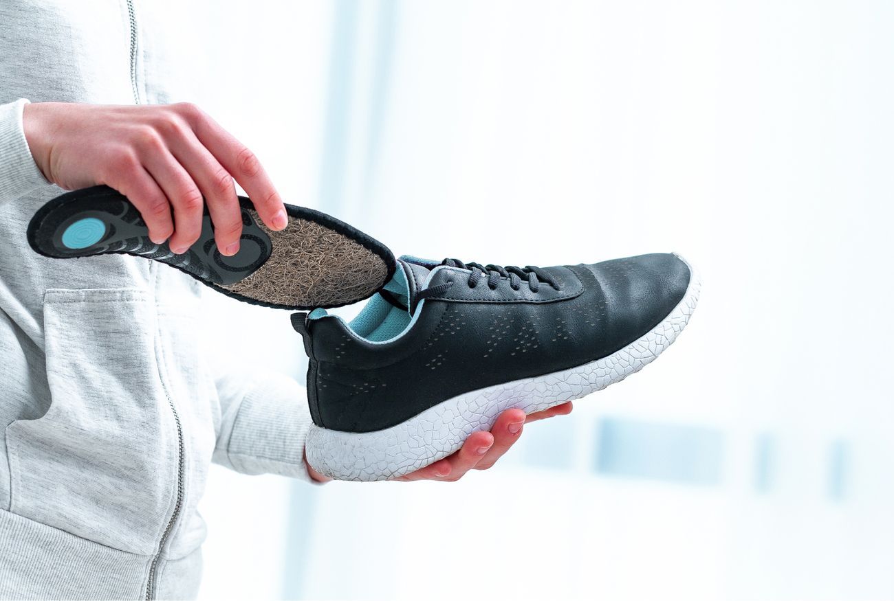 Eine Person legt Einlegesohlen in ein Paar Schuhe ein.