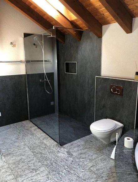 bagno con rivestimenti scuri e pavimento effetto pietra - EB 77 Pavimenti di Emanuele Benedetti