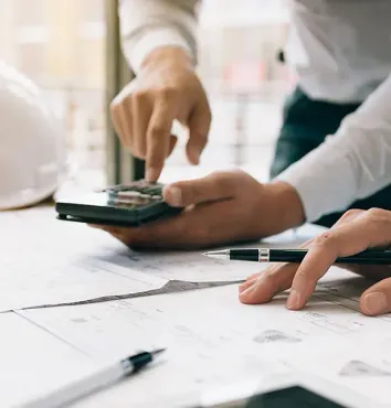 Una persona está usando una calculadora y un bolígrafo sobre una mesa.