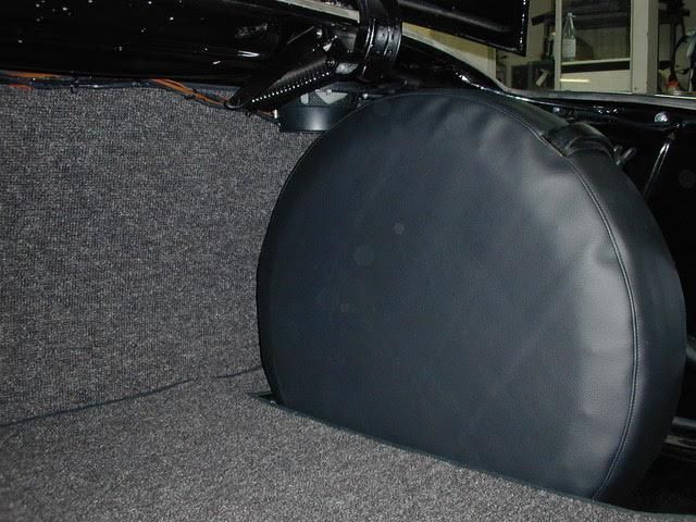 Im Kofferraum eines Autos liegt eine schwarze Reifenabdeckung.