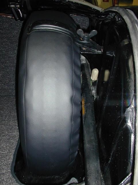 Im Kofferraum eines Autos liegt ein schwarzer Reifen.