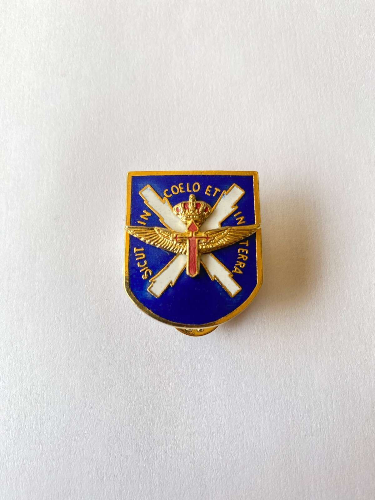 Pin de escudo de estilo militar azul y dorado con rifles cruzados y un emblema central.