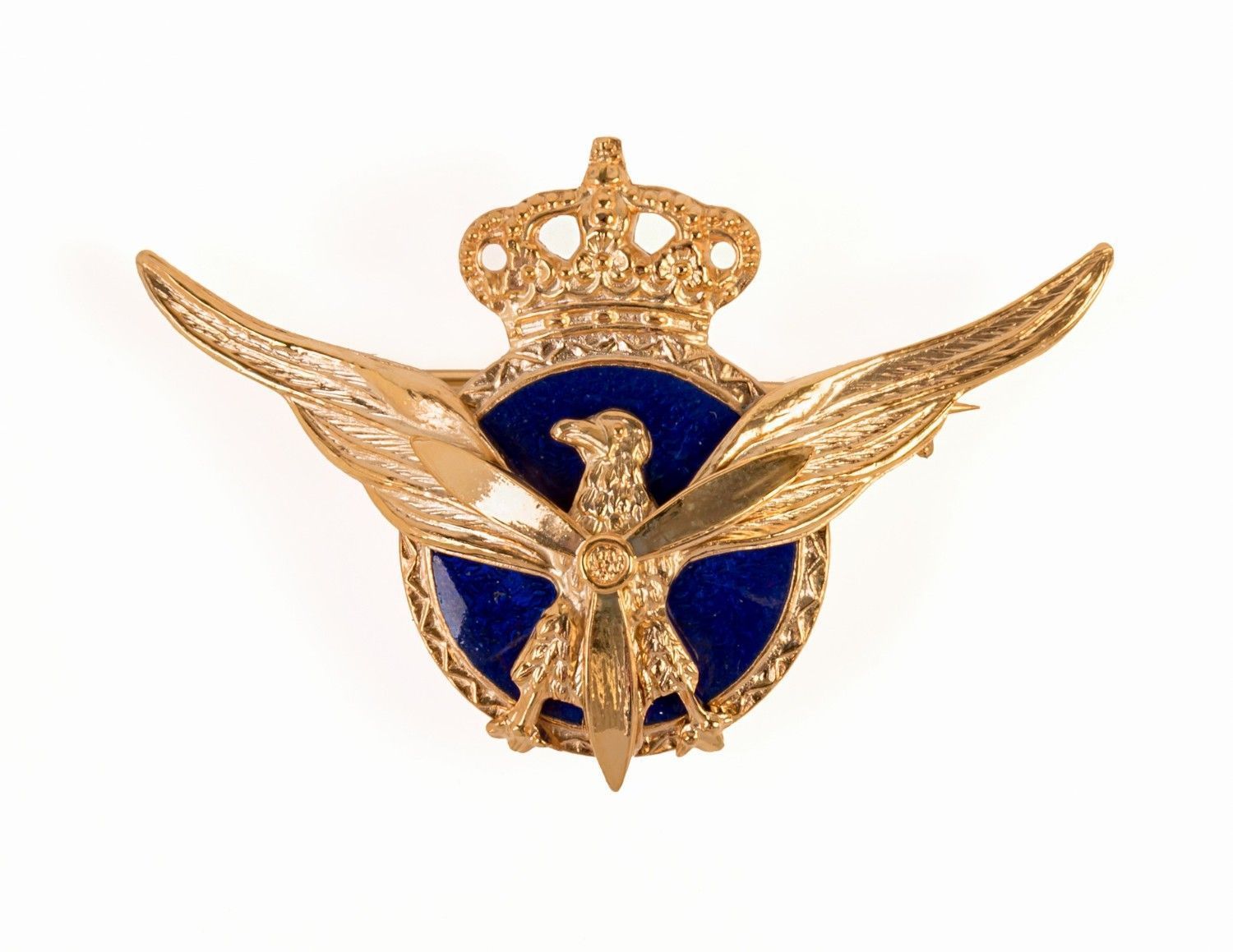 Emblema dorado con alas de águila sobre un fondo circular azul con una corona en la parte superior.