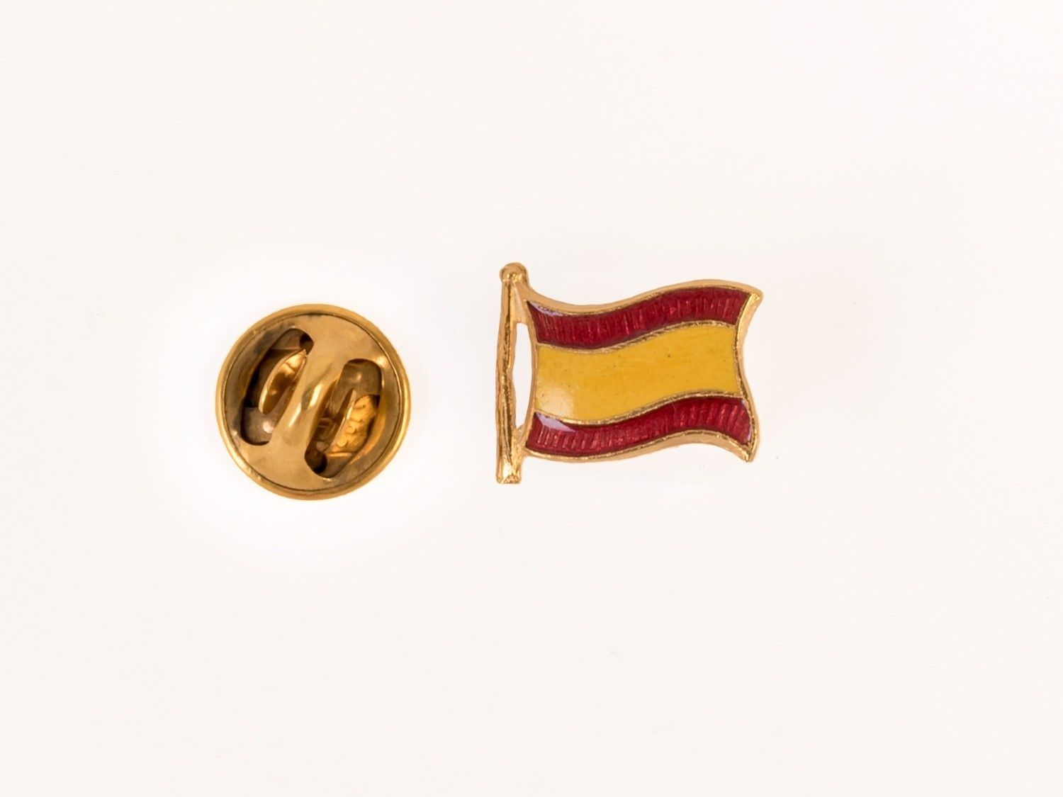 Pin dorado con un emblema de bandera roja y amarilla sobre fondo blanco.