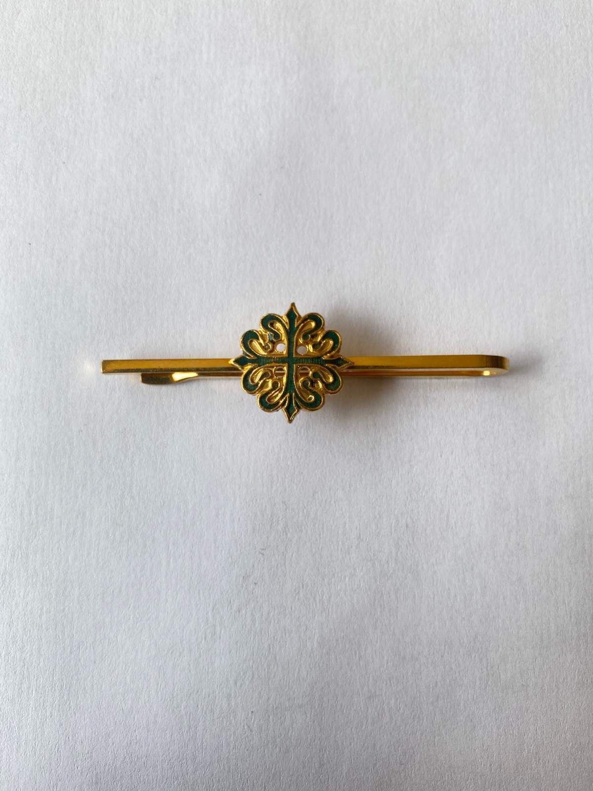 Broche de barra dorado con forma de flor y detalles verdes sobre fondo blanco.