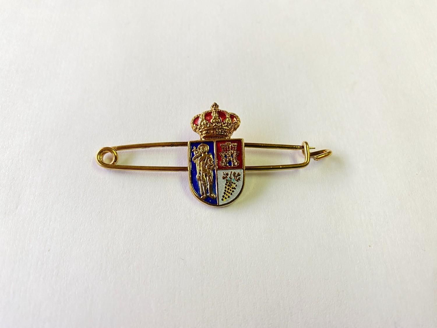Broche de oro con un escudo coronado en esmalte rojo, azul y blanco.