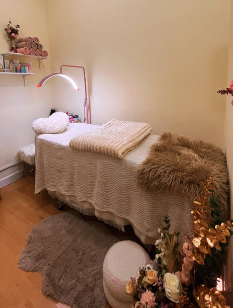 Acogedor dormitorio beige con una cama bien hecha, manta de pelo sintético, lámpara de pie, alfombra y decoración suave en tonos neutros.