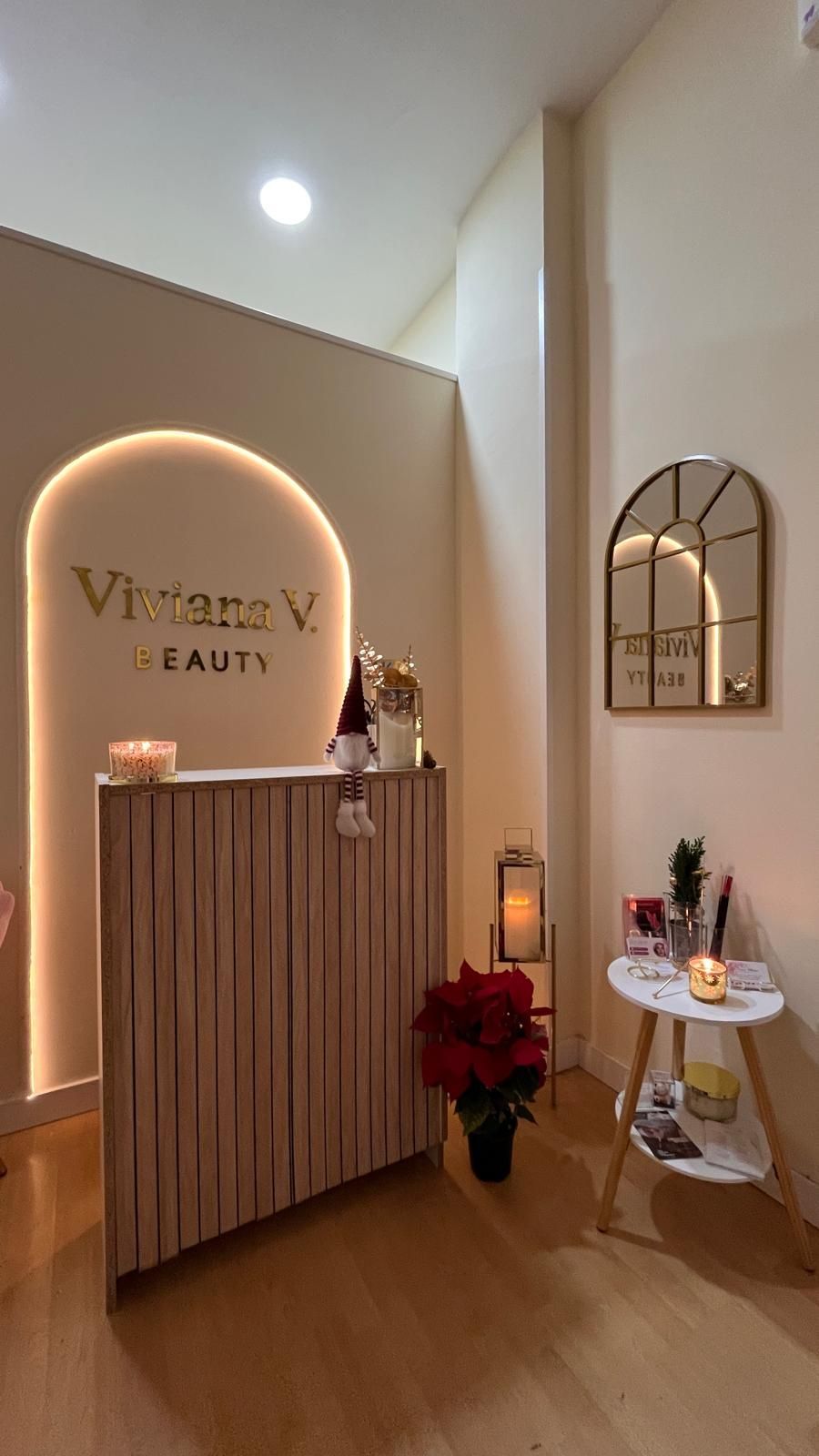 Recepción elegante de salón de belleza con cálida decoración de madera, letrero de neón arqueado, espejo y una pequeña mesa de exposición.