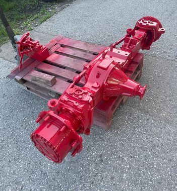Rot lackierte LKW-Achse auf einer Holzpalette, im Freien.