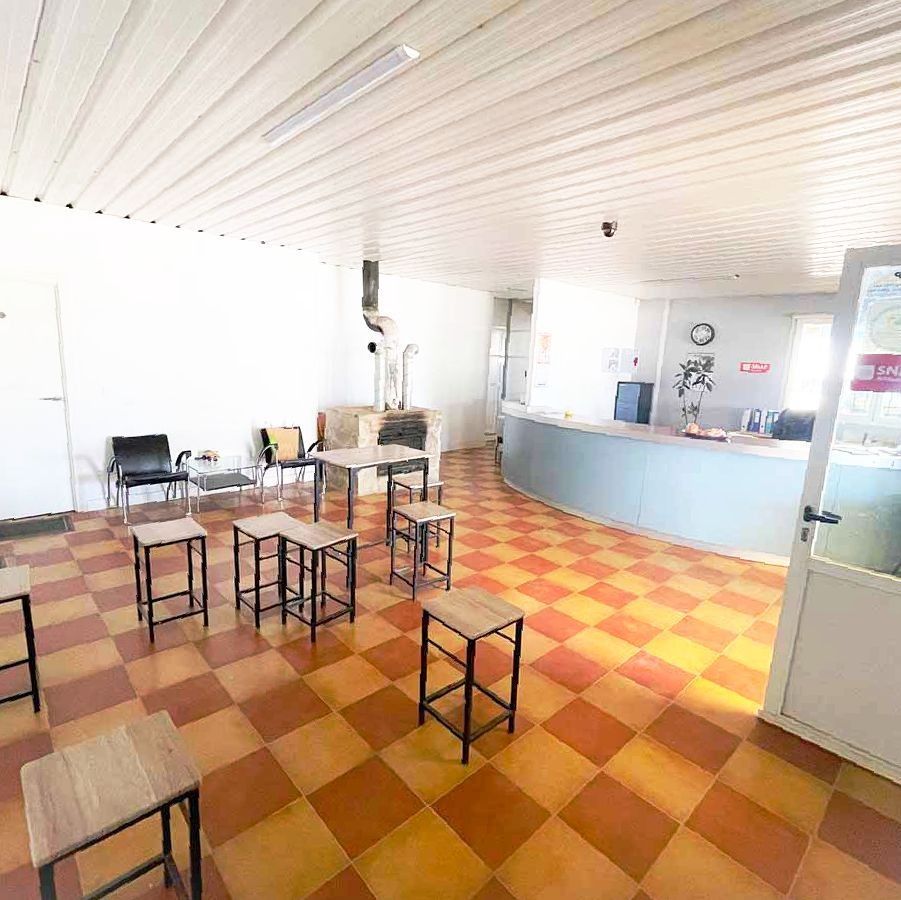 Una sala de espera vacía con suelo cuadriculado, taburetes y un mostrador de recepción.