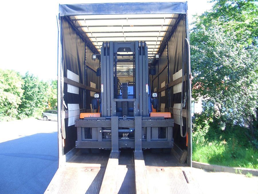 Gabelstapler in einem LKW-Anhänger, bereit für den Transport. Maschinen in Schwarz, Grau und Orange.