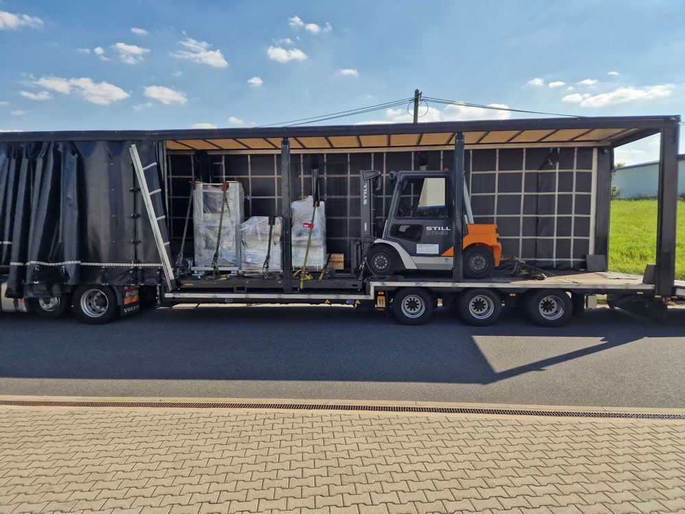 Gabelstapler und Ladung auf einem Tieflader, beladen mit Säcken. Sonniger Tag, Straßenszene.