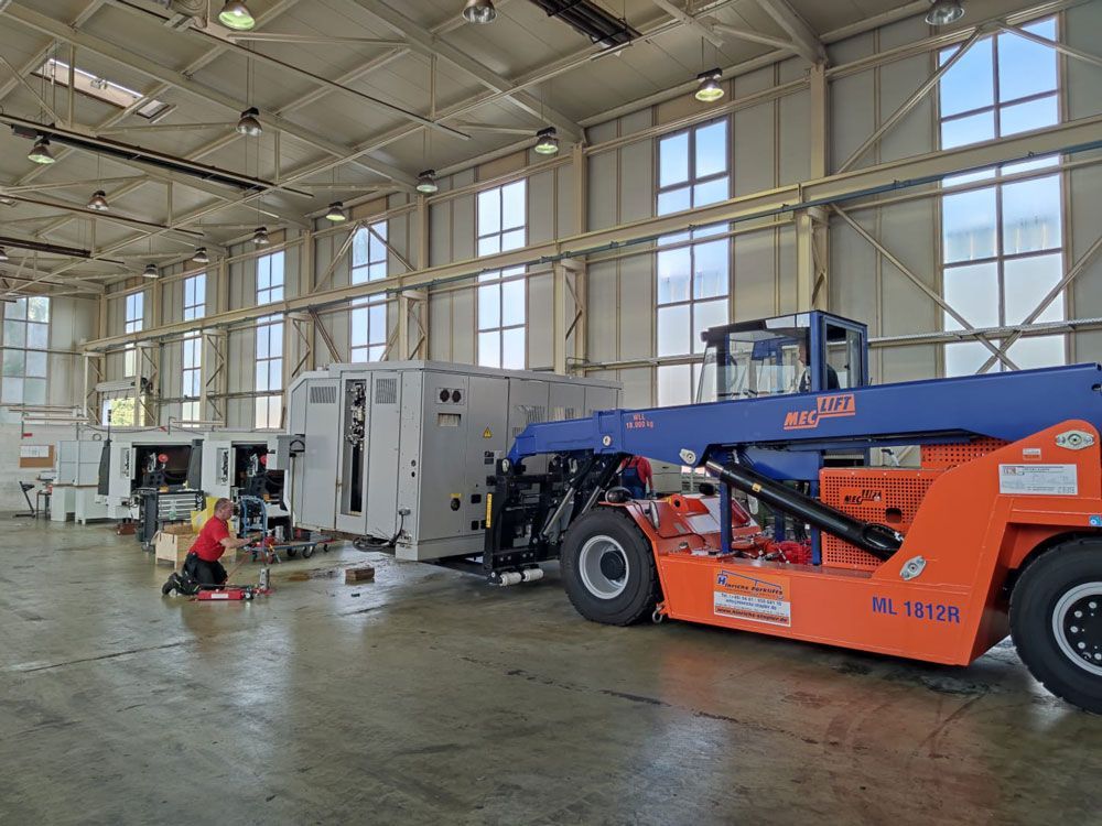Ein Gabelstapler transportiert Ausrüstung in einem Lagerhaus, Arbeiter befinden sich in der Nähe.
