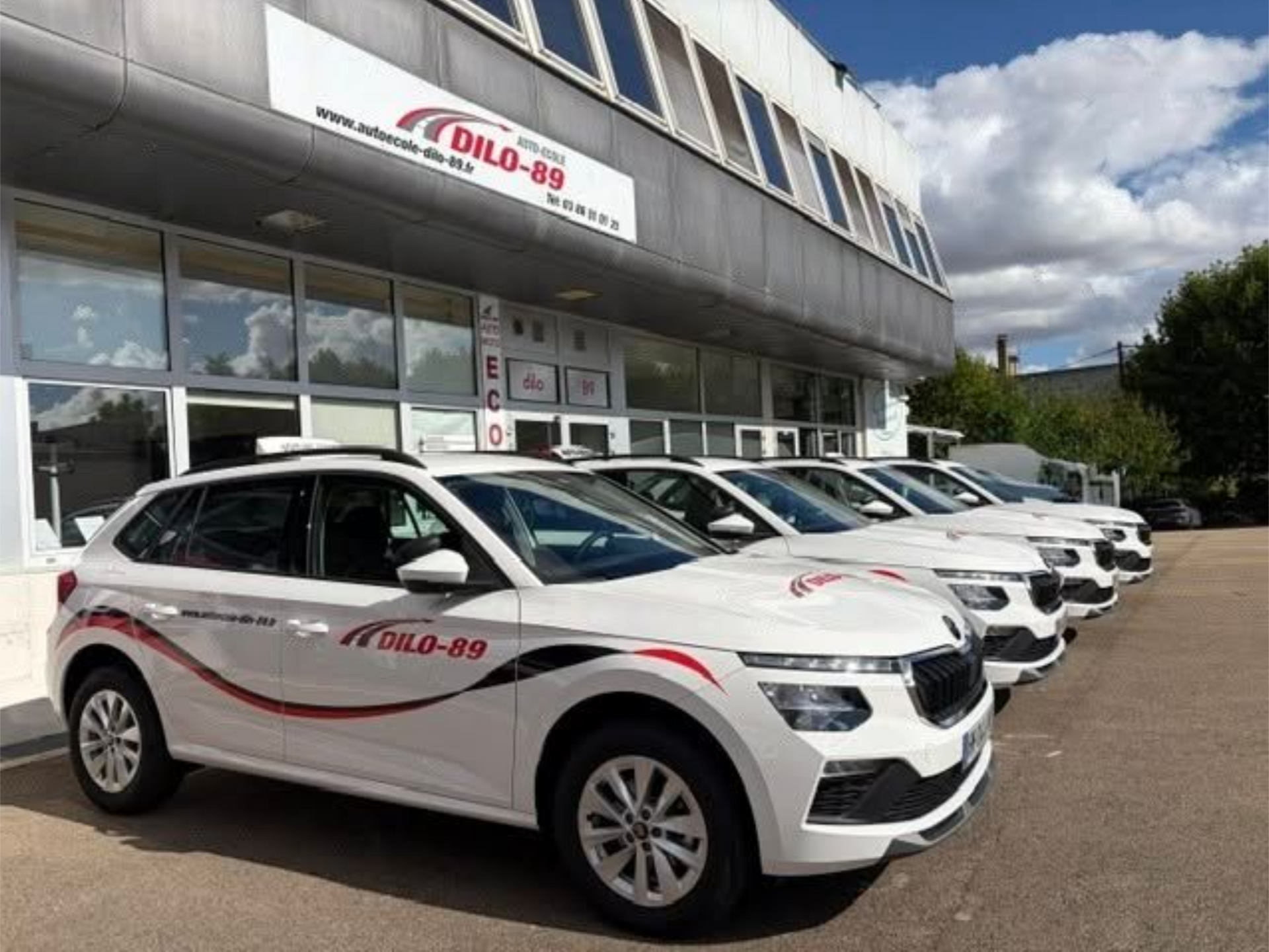 Voiture garée devant une boutique aux portes vitrées et une enseigne rouge et blanche au-dessus de l'entrée.