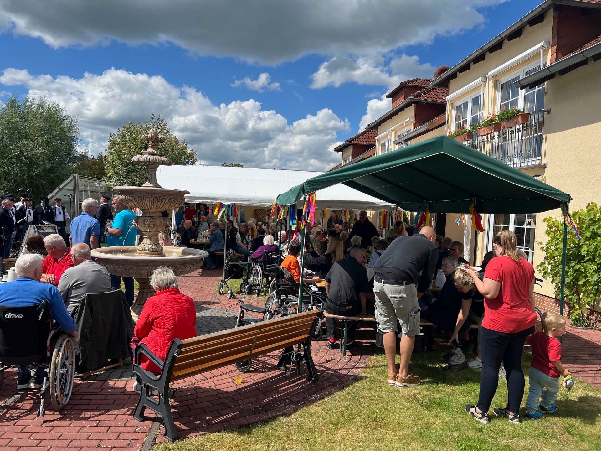 Eine Gruppe von Menschen sitzt auf Bänken in einem Park.