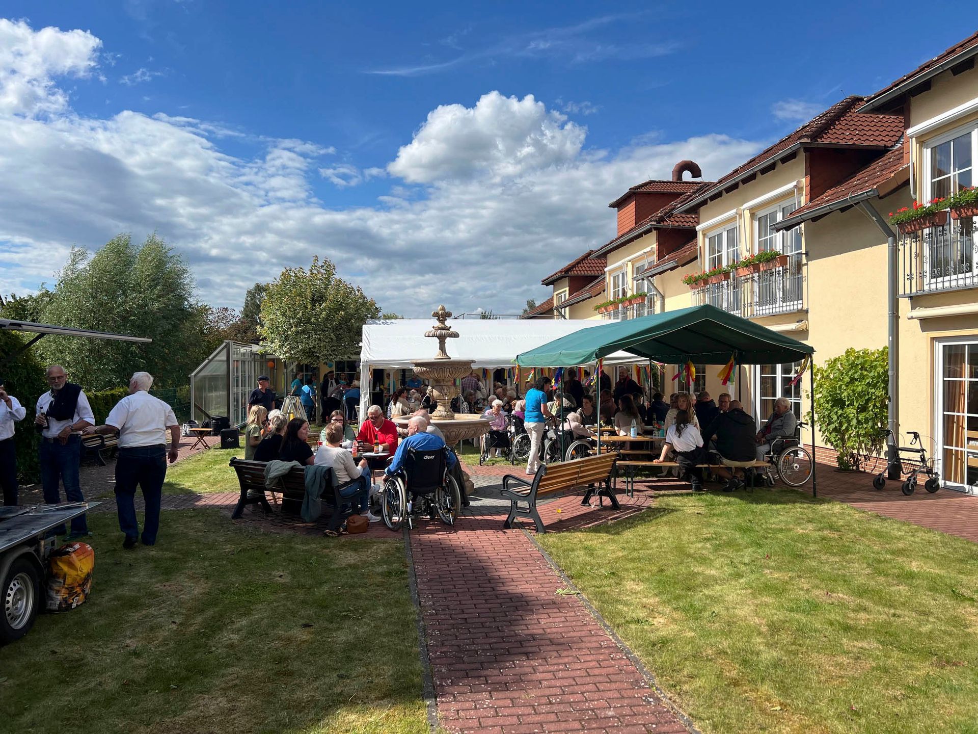 Eine Gruppe von Leuten sitzt unter einem Zelt in einem Hinterhof.