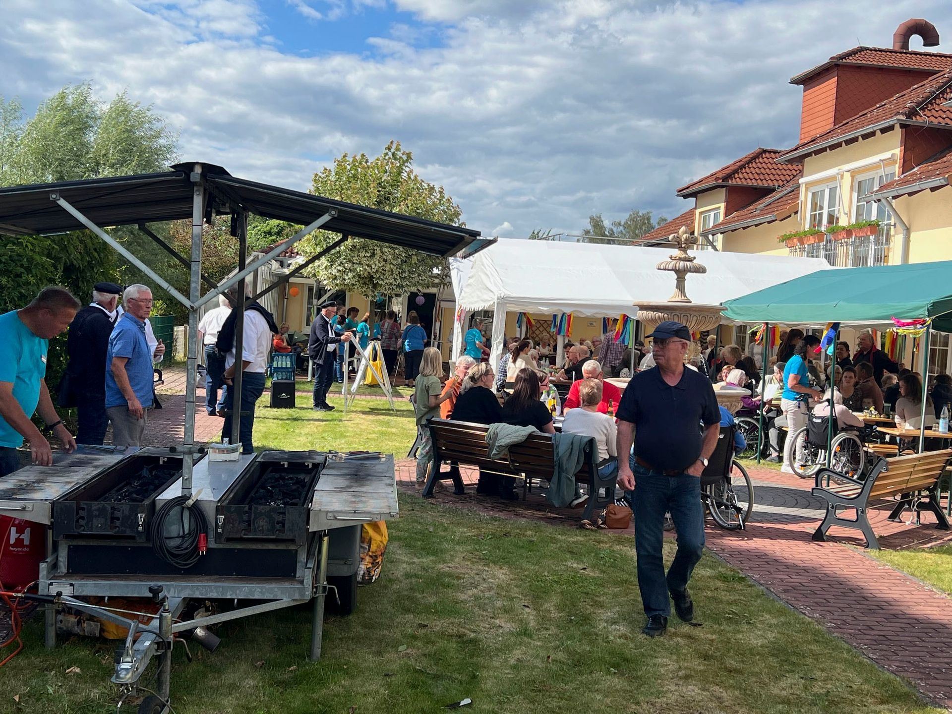 Eine Gruppe von Leuten steht in einem Park um einen Wohnwagen herum.