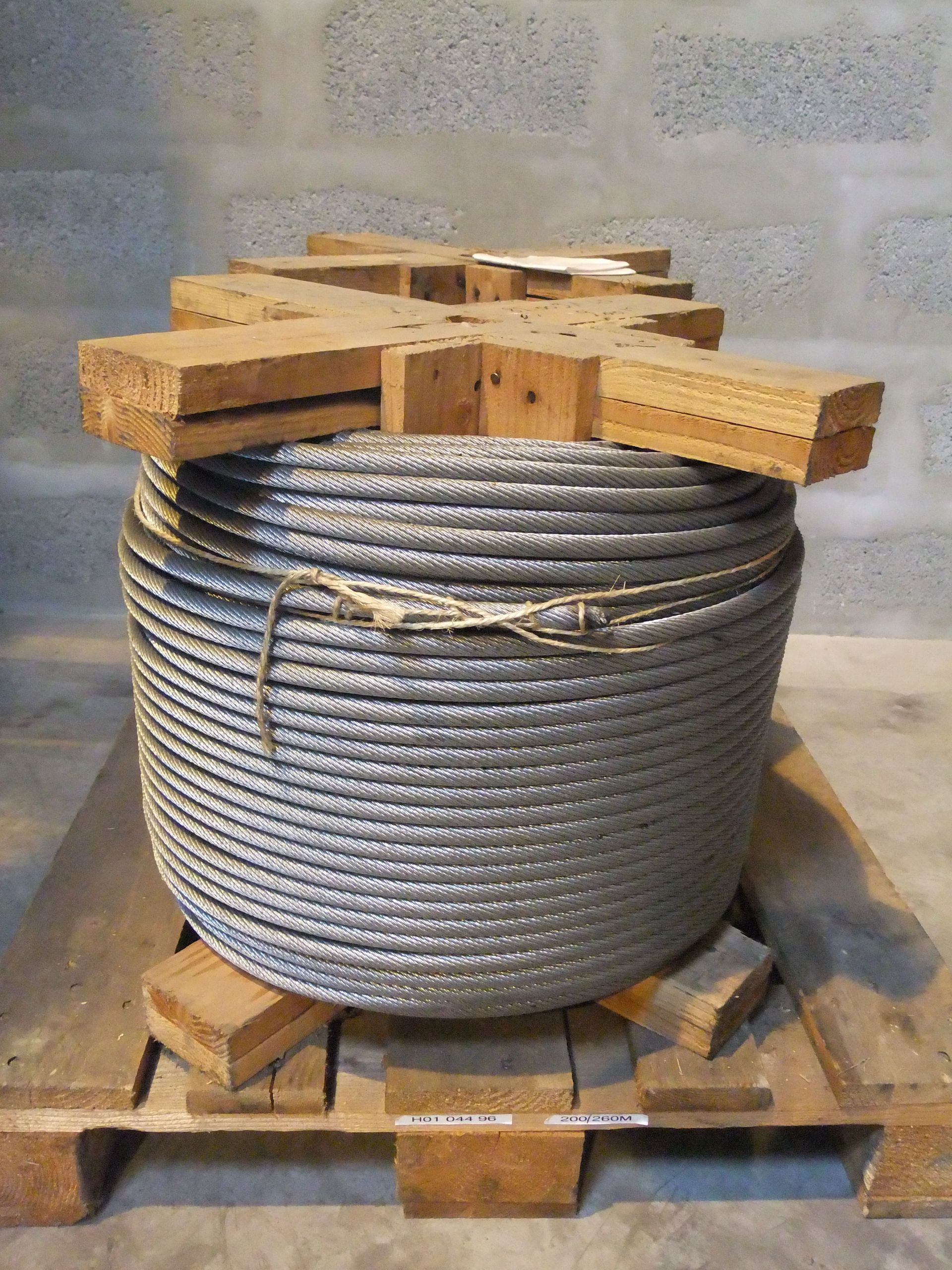 Une haute grue de chantier se dresse sur un flanc de montagne verdoyant, devant un petit bâtiment. Ciel d'un bleu éclatant.