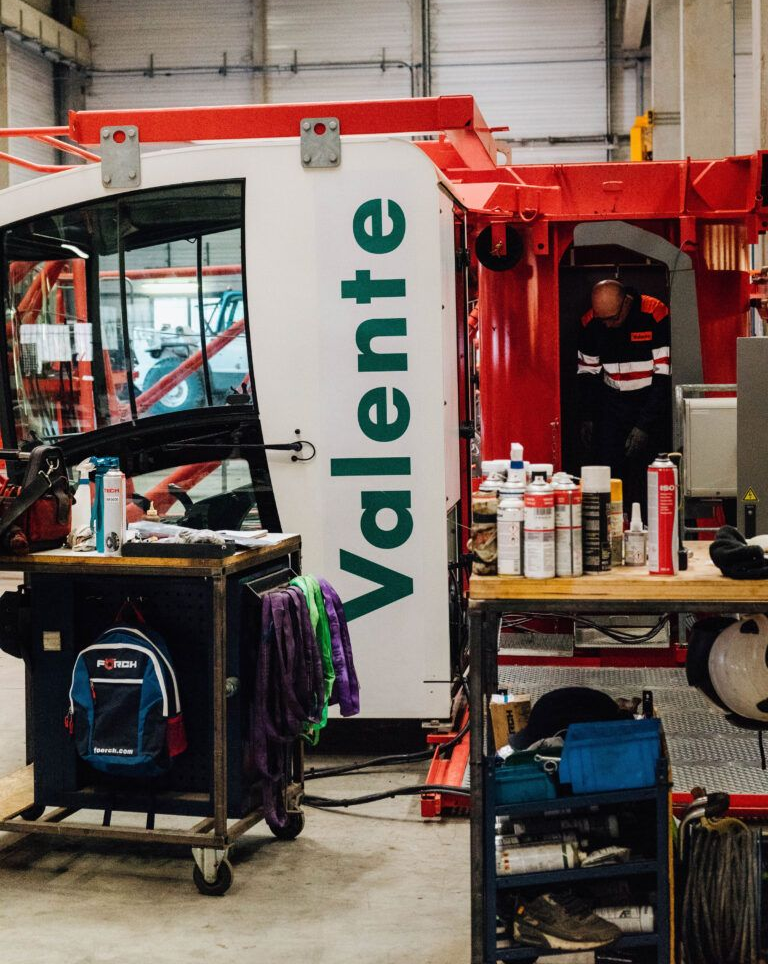 Machines blanches et rouges avec le logo ; ouvrier en arrière-plan ; établi avec fournitures.