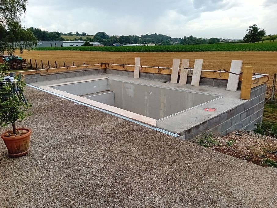 Piscine en construction bordée par une terrasse.