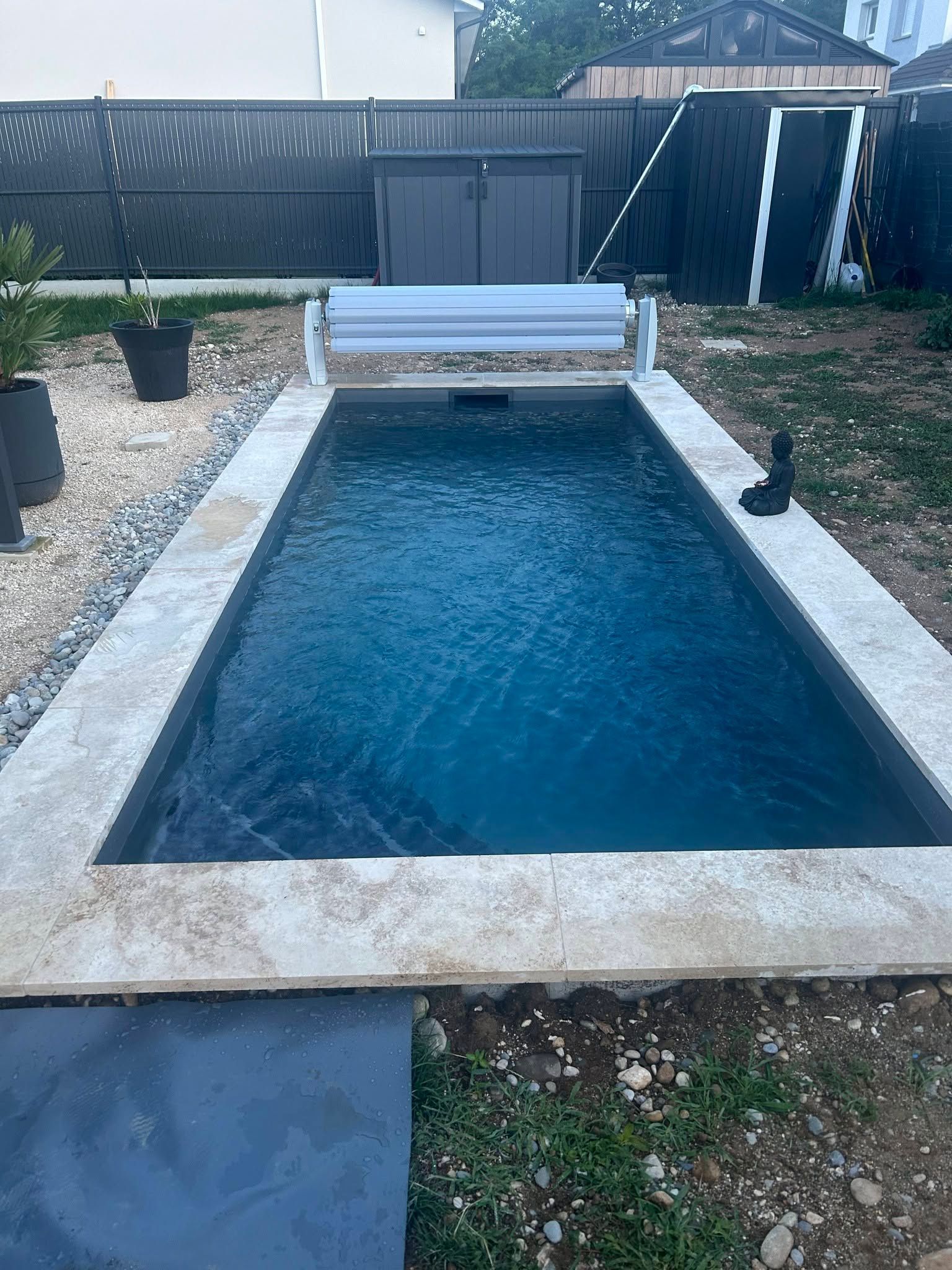 Piscine rectangulaire dans le jardin, avec eau bleue, bordure blanche.