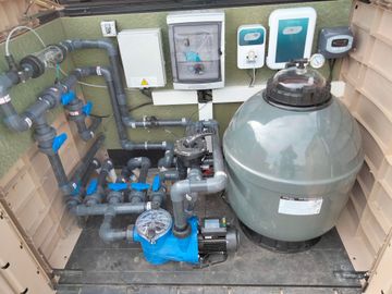 Équipement de filtration de piscine avec réservoir d'eaux, pompe à eaux, tuyaux et boîtiers de commande.