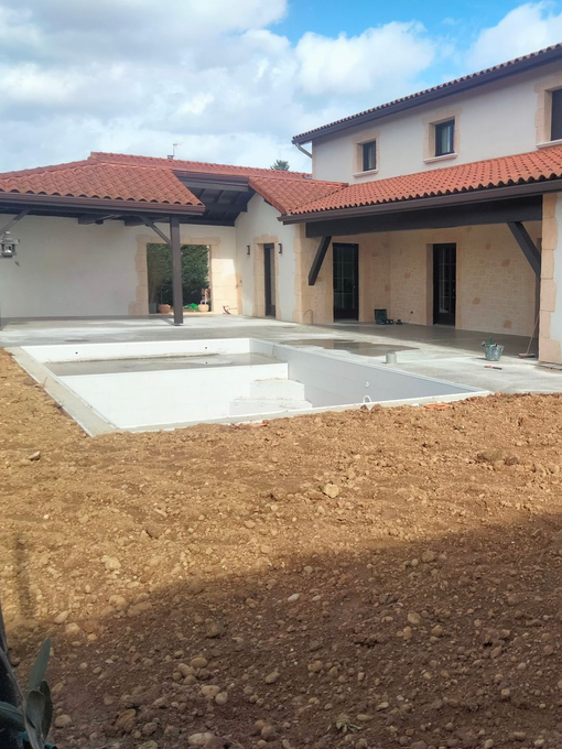 Cour intérieure avec une grande piscine à côté d'une maison aux tuiles rouges.