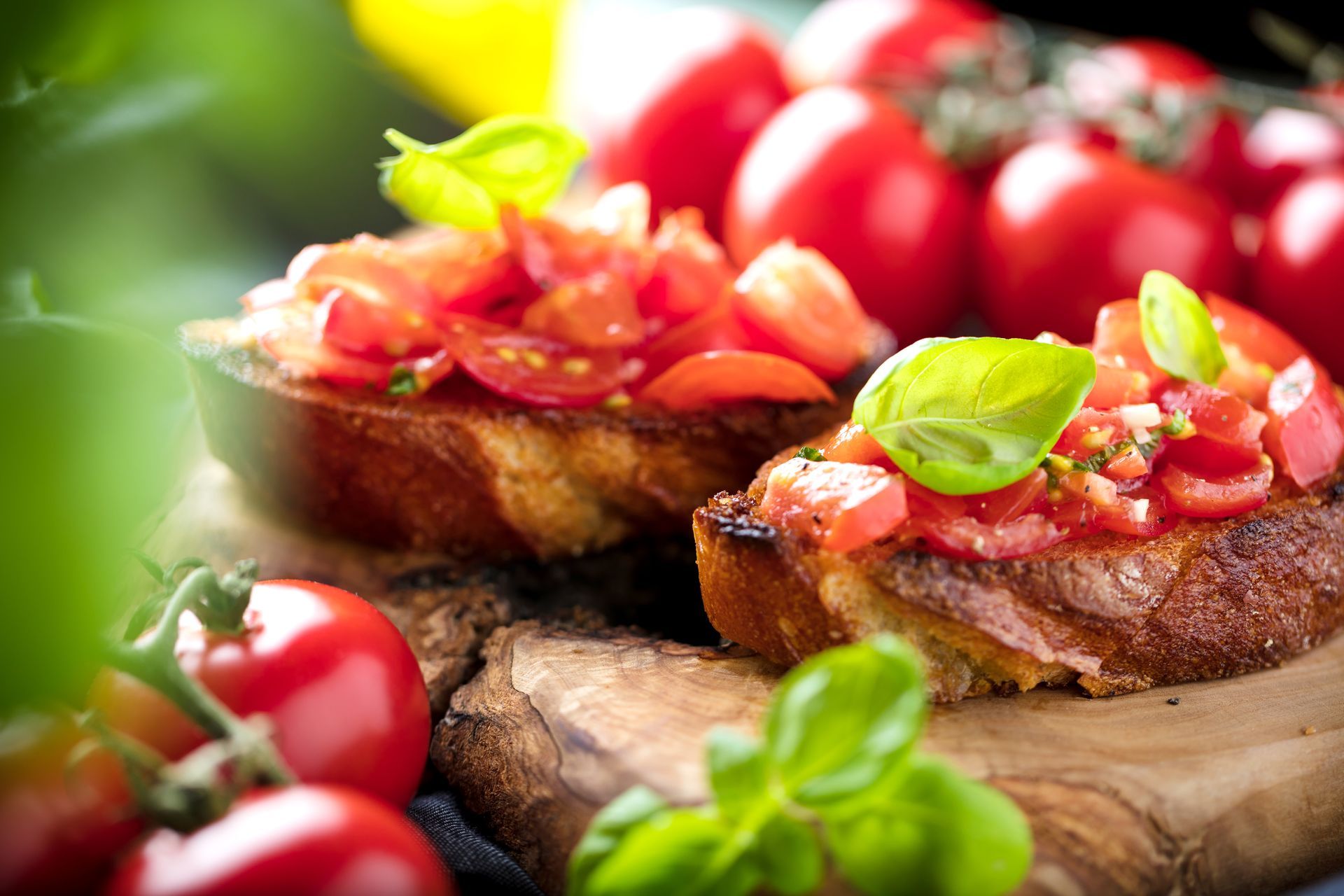 Bruschetta à la tomate et au basilic sur du pain grillé, présentée sur une planche en bois, avec des tomates cerises fraîches à proximité.